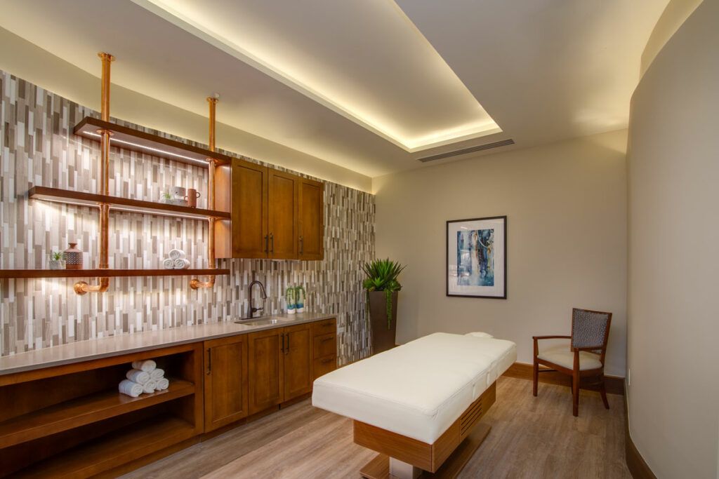 A serene and modern massage room featuring a therapy table, wooden cabinets, and calming decor.