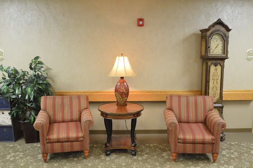 A cozy seating area with two striped chairs and a table featuring a lamp.