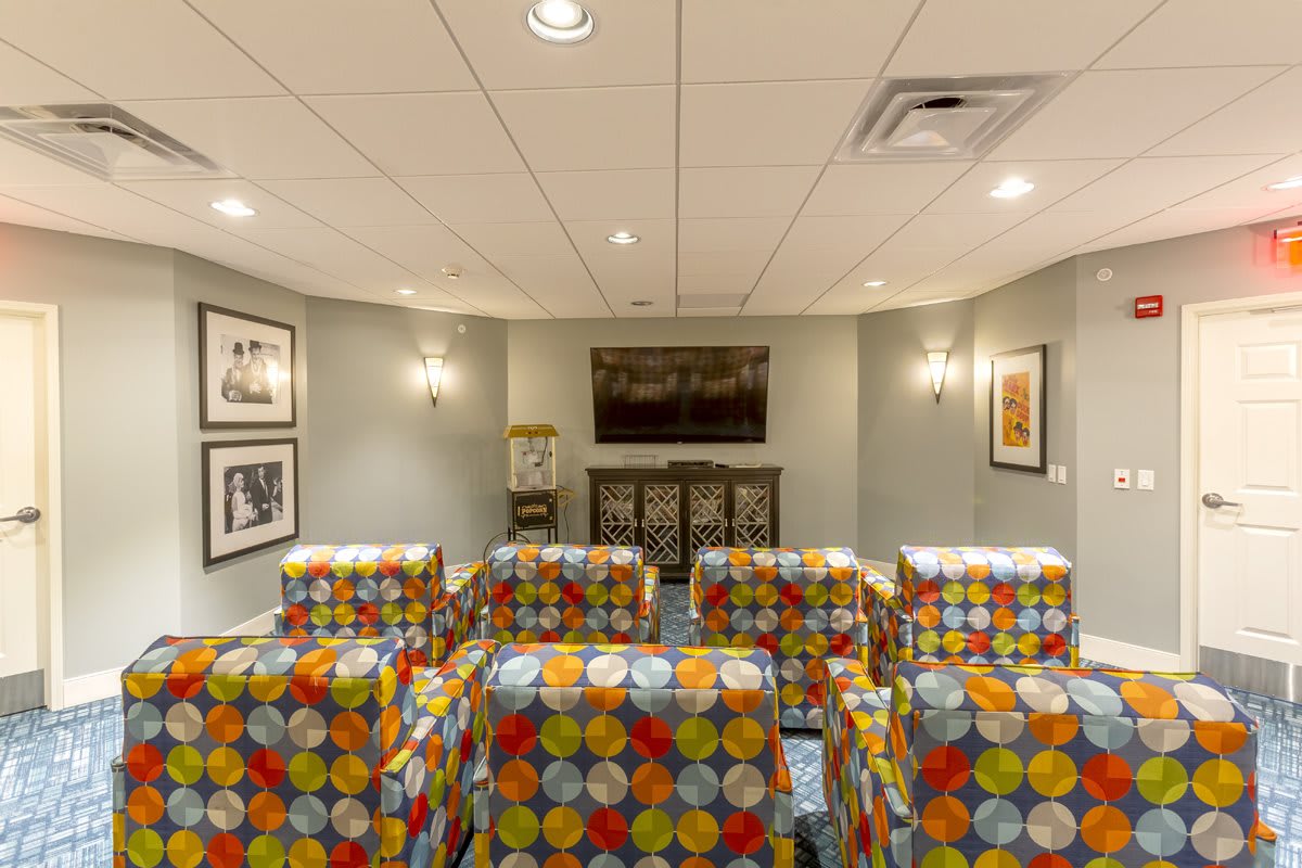 A cozy home theater with colorful patterned chairs and artwork adorning the walls.