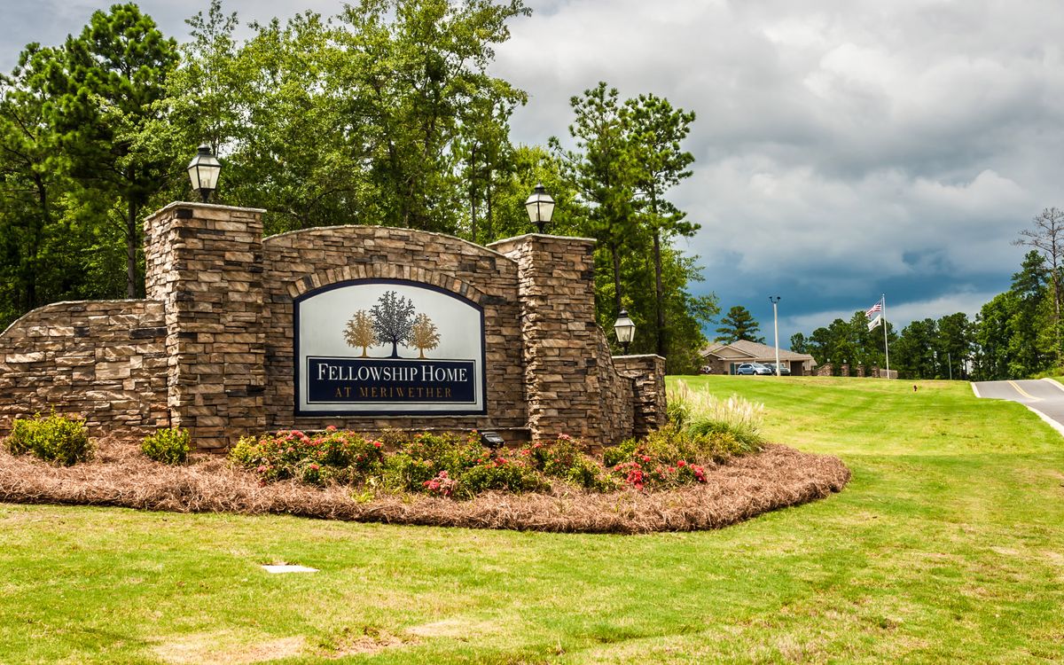 Entrance sign of a neighborhood surrounded by greenery and stone pillars.