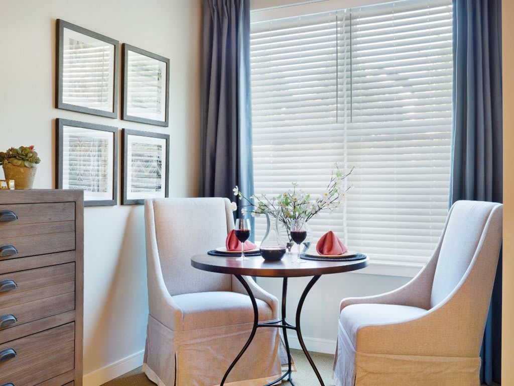 A cozy dining area with a round table and two upholstered chairs, adorned with decorative accents and artwork on the wall.
