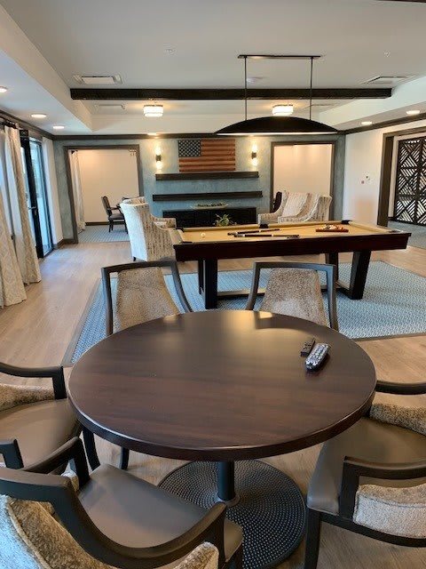 A modern living room with a pool table, round table, and comfortable seating.