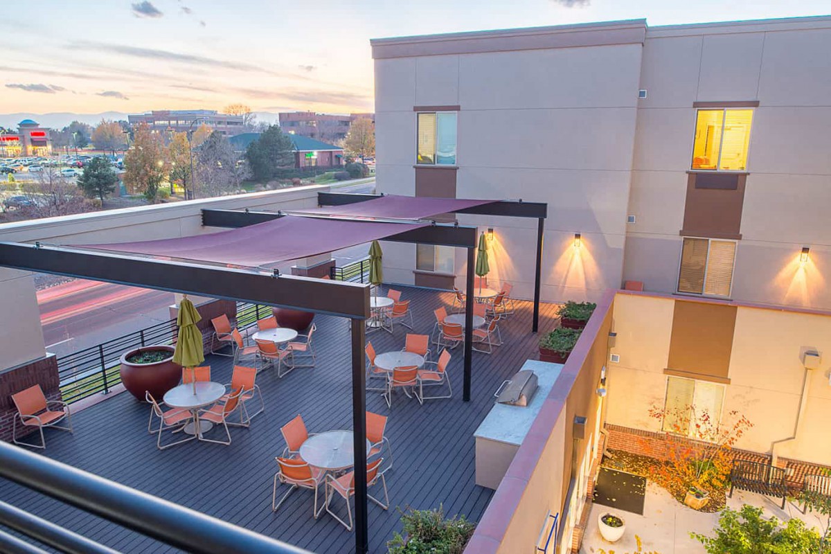 A rooftop patio with outdoor seating and pergola at sunset.