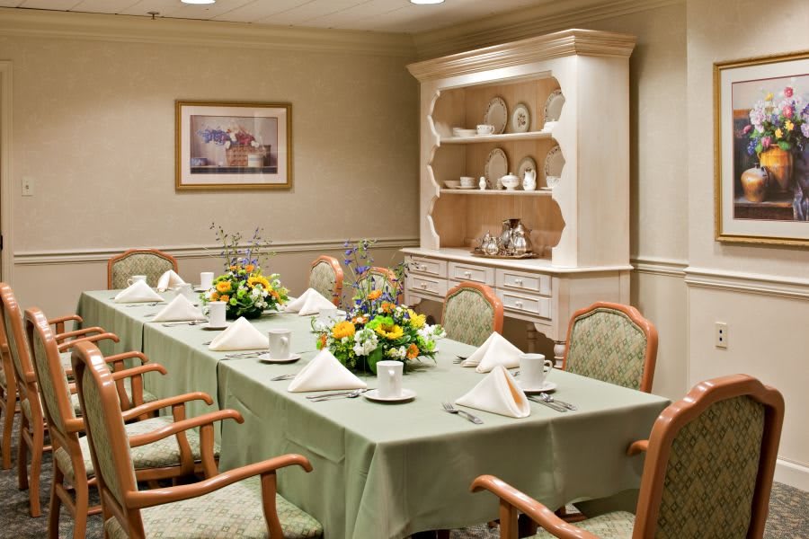 A formal dining room with a beautifully set table and elegant flower arrangements.
