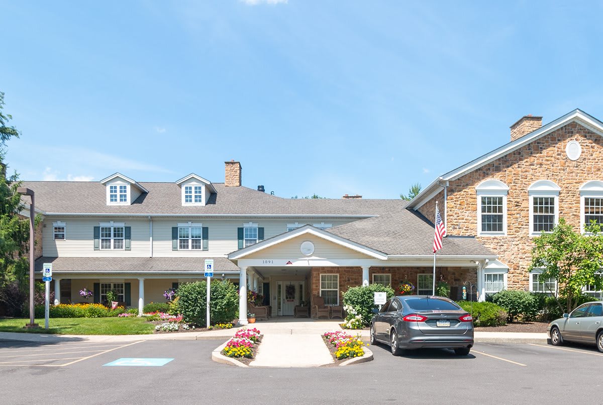 A building with a driveway and car, surrounded by well-maintained landscaping under a clear sky.