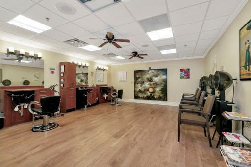 A spacious and well-lit salon featuring barber chairs, a waiting area, and ceiling fans.