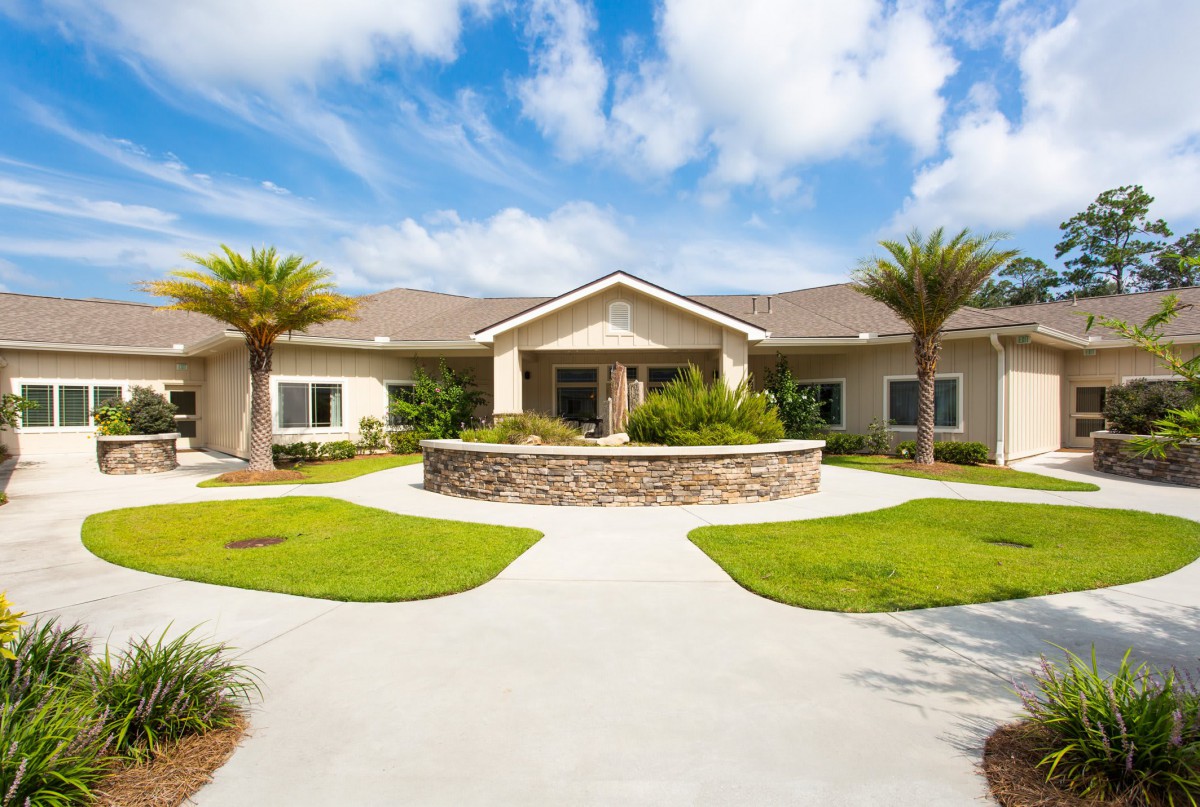 A modern residential house with a landscaped front yard and palm trees.