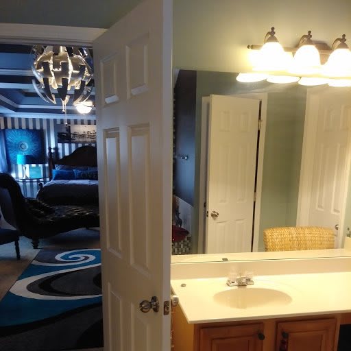 A view of a bedroom and bathroom, connected by an open door, showcasing modern interior design with elegant lighting.