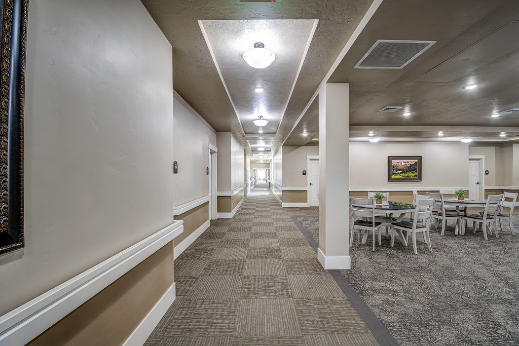 A well-lit hallway with carpeted flooring and a seating area.