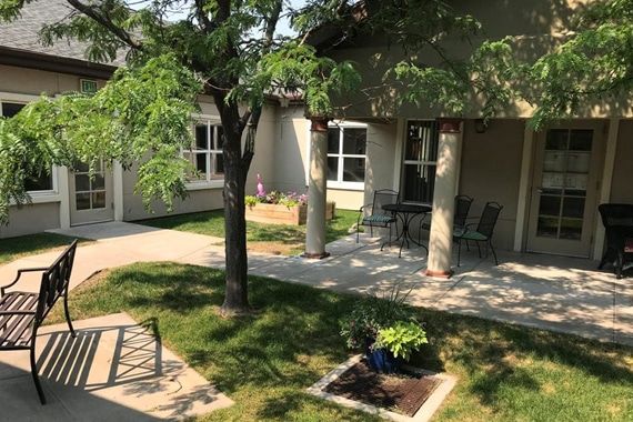 A peaceful courtyard with a garden, featuring trees and outdoor seating.