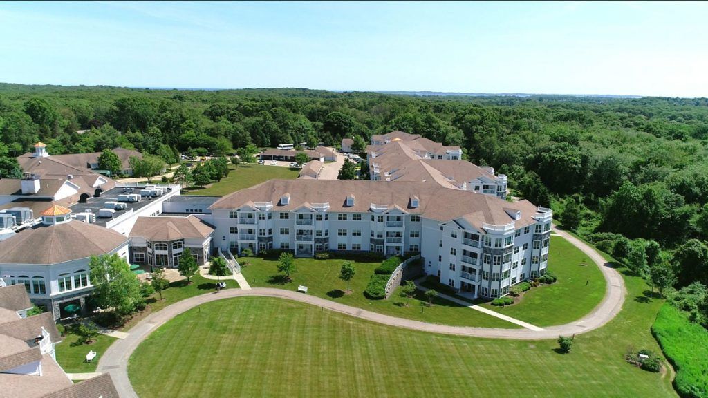 Aerial view of a large residential apartment complex surrounded by green lawns and trees.