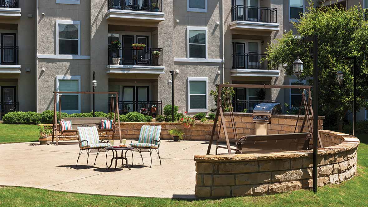 Outdoor patio area with seating in front of an apartment building.