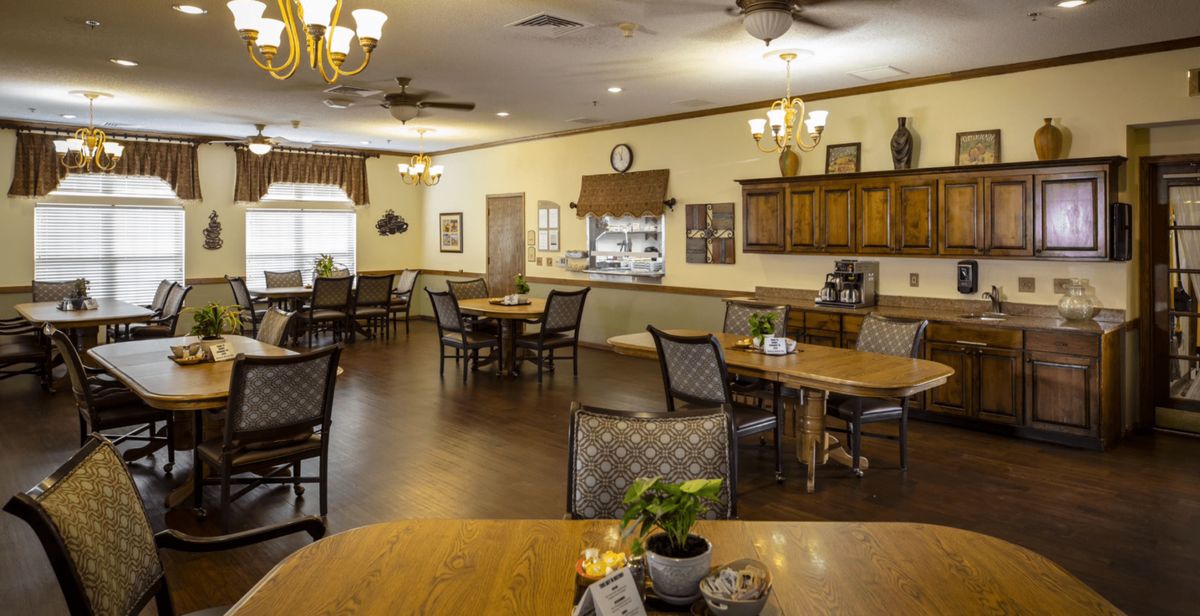 A cozy dining room with neatly arranged tables and chairs, warm lighting, and tasteful decor.