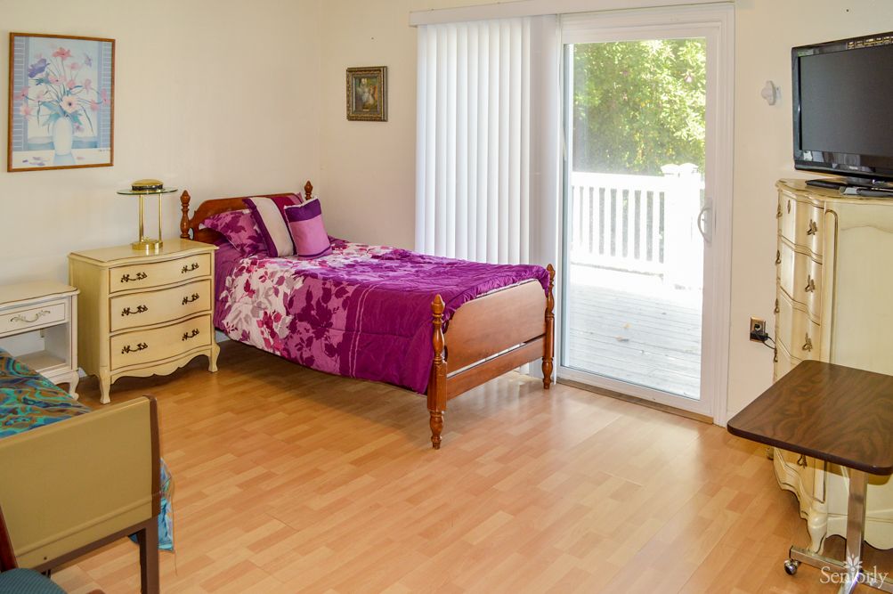 A cozy bedroom with a single bed and a view of the balcony through sliding glass doors.