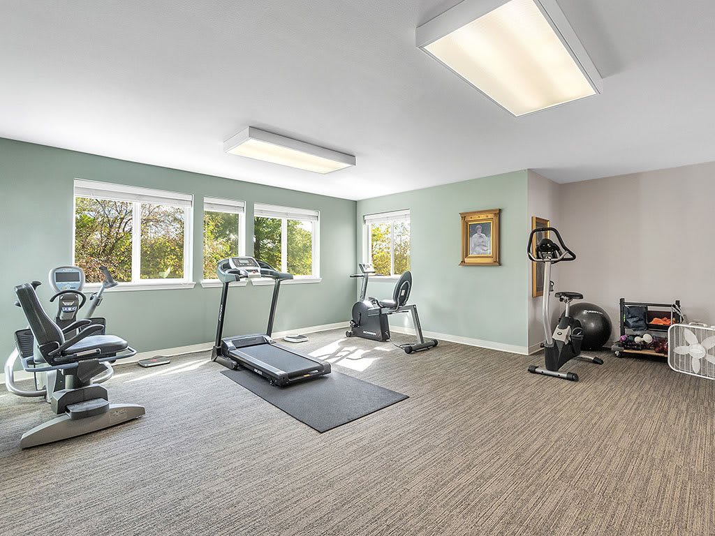 A bright and spacious gym with exercise equipment including treadmills and a stationary bike.
