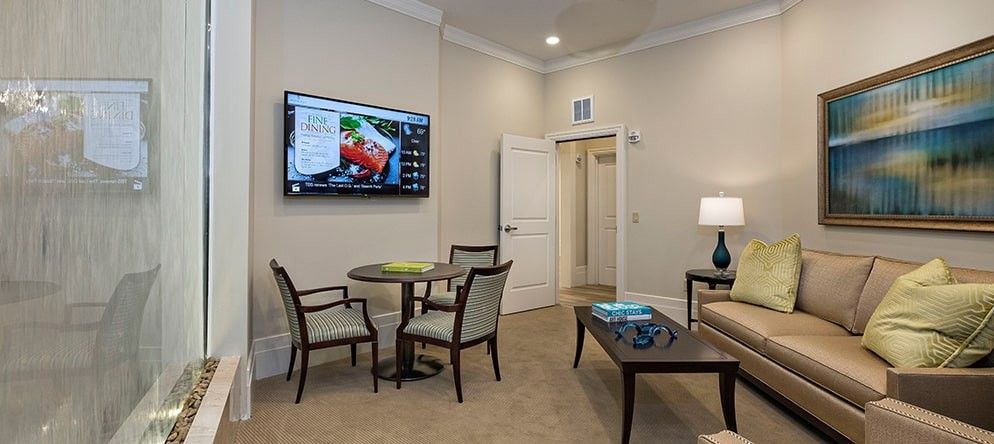 A cozy living room featuring a television, small dining table with chairs, and a comfortable sofa.
