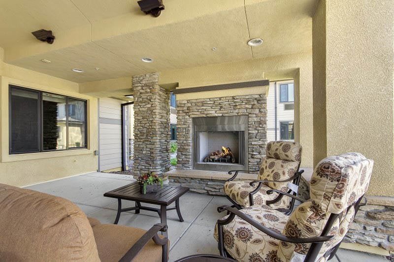 A cozy outdoor patio with a stone fireplace and comfortable seating.
