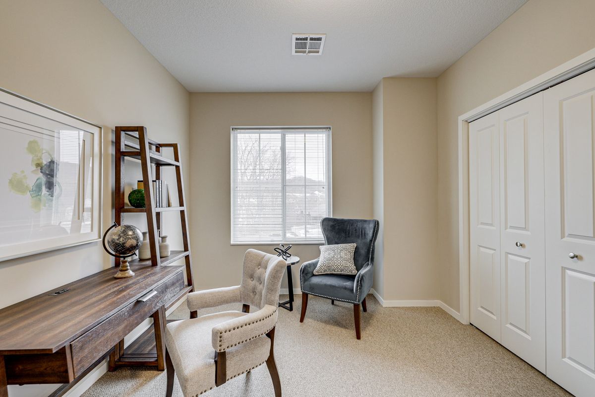 A cozy home office space with a desk, chair, bookshelf, and window.