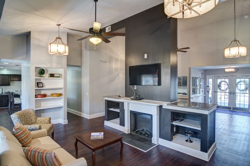 Modern living room with a fireplace and TV, featuring wood flooring and elegant light fixtures.