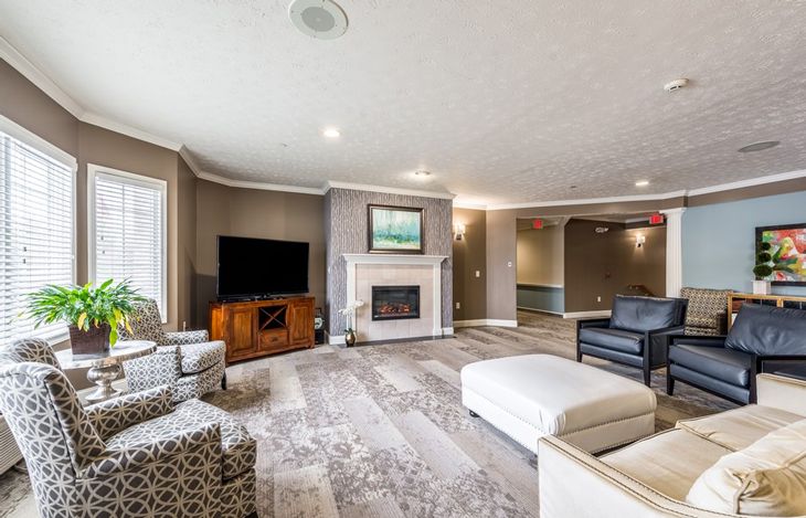 A spacious living room featuring modern furnishings, a fireplace, and a large television.
