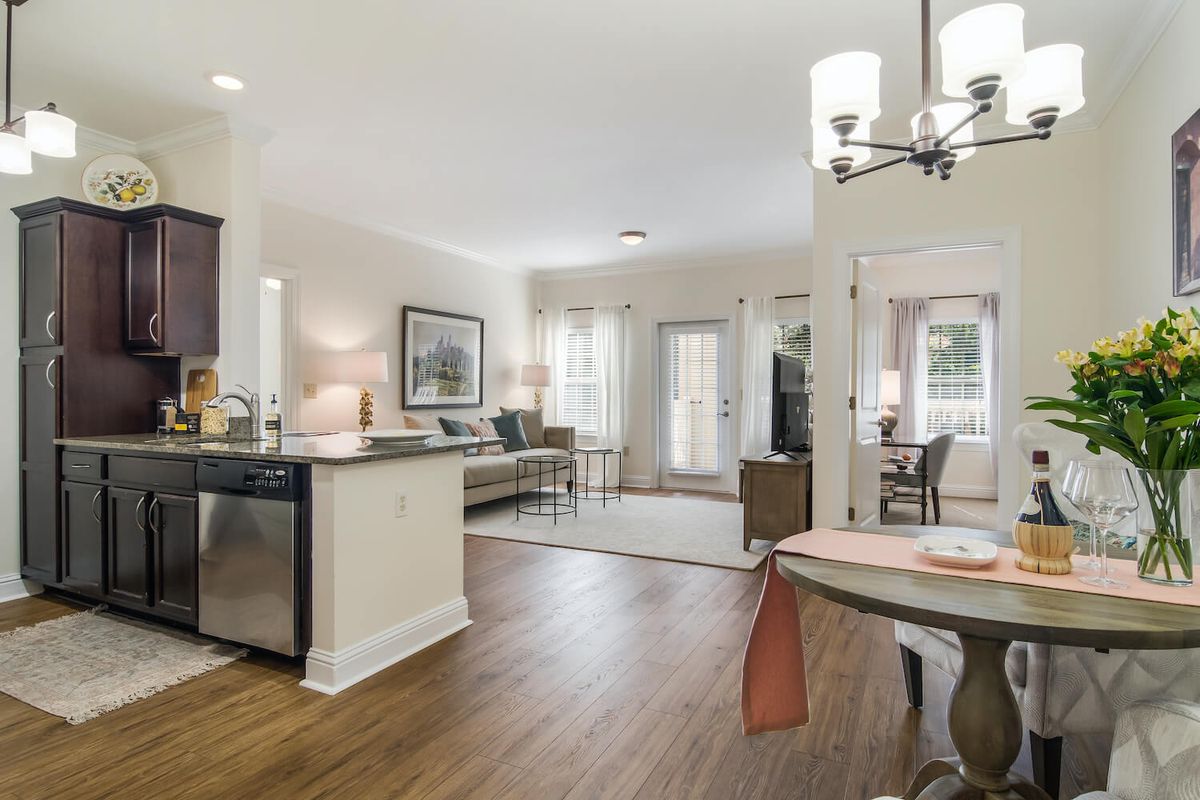 A modern open floor plan featuring a kitchen, living room, and dining area with hardwood floors and ample natural light.