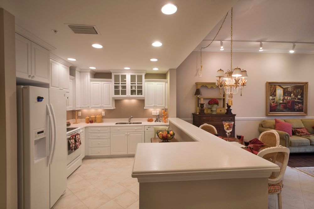 A modern kitchen with white cabinets and ambient lighting, featuring an open layout.