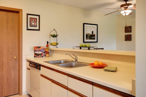 A modern kitchen featuring a clean countertop with fresh fruits and decorative wall art.