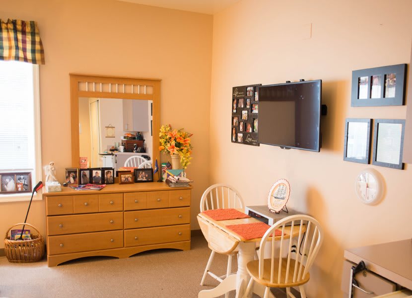 Cozy room with a dresser, mirror, wall-mounted TV, and small dining area.