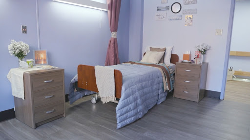 A well-furnished hospital room featuring a bed, nightstand, and decorative elements.