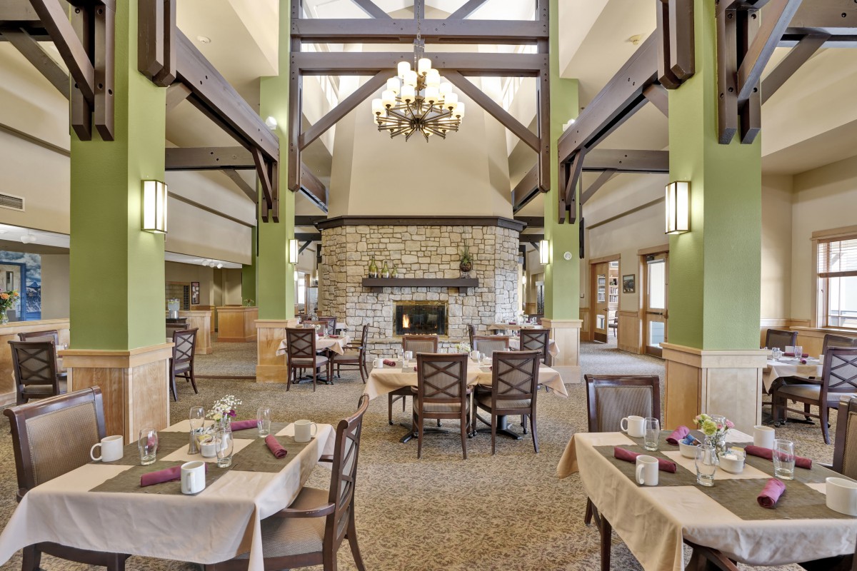 A spacious dining room with elegant decor, featuring a central fireplace and a chandelier.