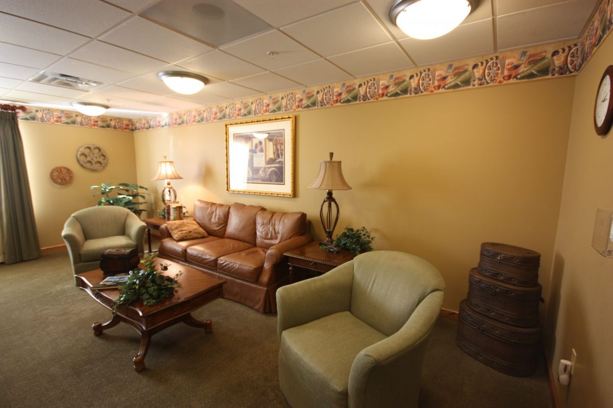 A cozy waiting room with comfortable sofas and armchairs, warm lighting, and decorative plants.