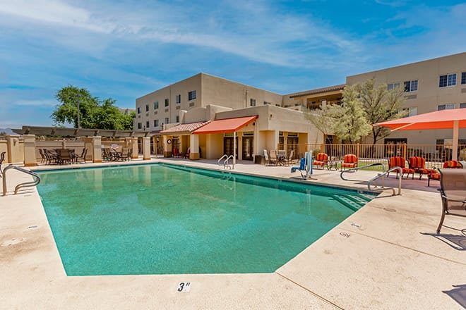 An outdoor swimming pool area at a hotel with clear blue skies.