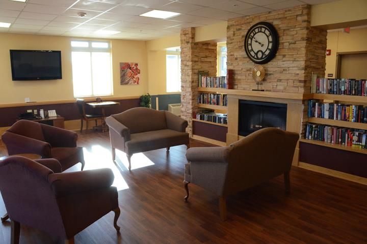 A cozy living room with comfortable seating, a fireplace, and bookshelves.
