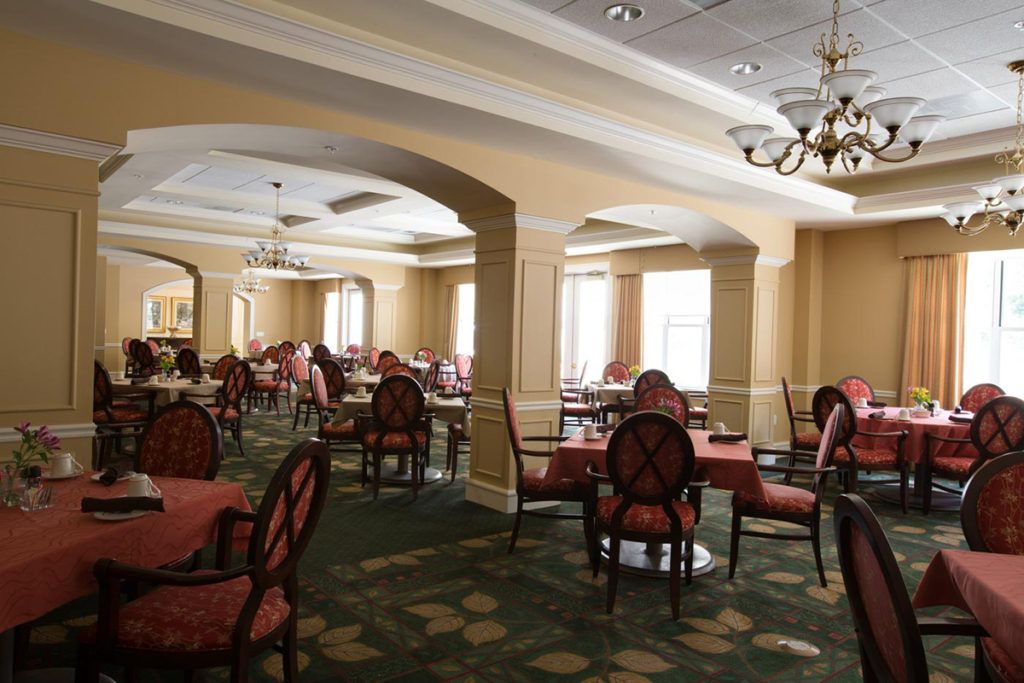 An elegant empty dining room with chandeliers and neatly arranged tables and chairs.