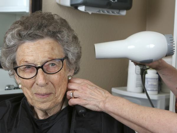 An elderly woman is getting her hair styled at a salon.