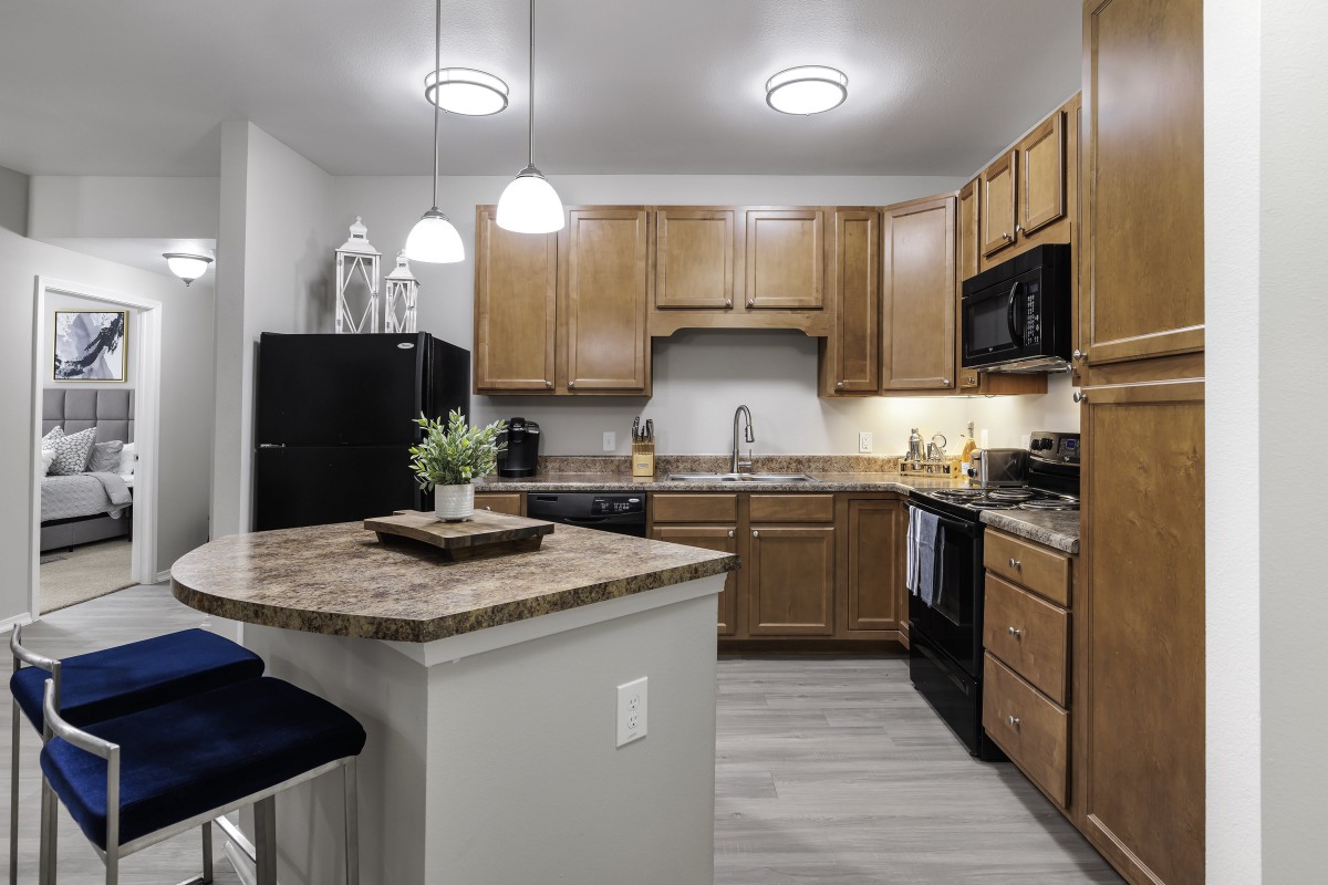 A modern kitchen featuring wooden cabinets, a central island, and contemporary appliances.