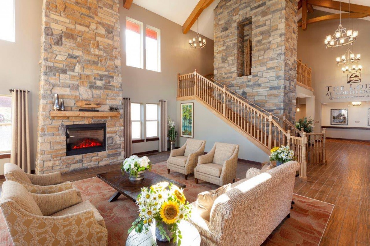 A spacious living room with a stone fireplace, high ceiling, and elegant furniture.
