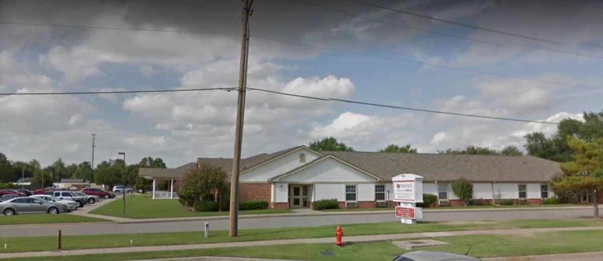 A clinic building with a sign and a cloudy sky in the background.