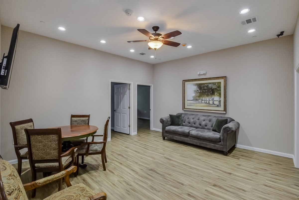 A cozy living room with a seating area, wooden flooring, and a ceiling fan.
