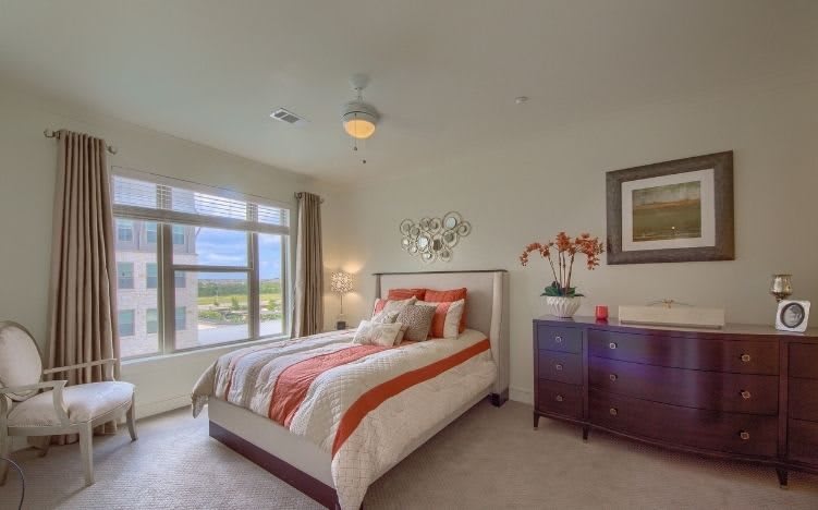 A modern bedroom with a neatly made bed and bright natural light.