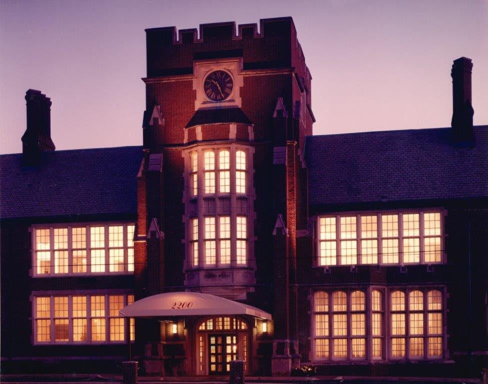 A historic building with a central clock tower illuminated in the evening.