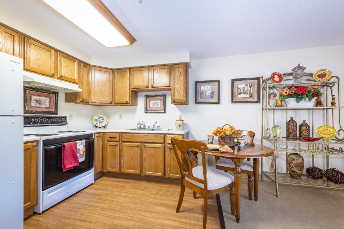A cozy kitchen with wooden cabinets, a small dining table, and wall decor.