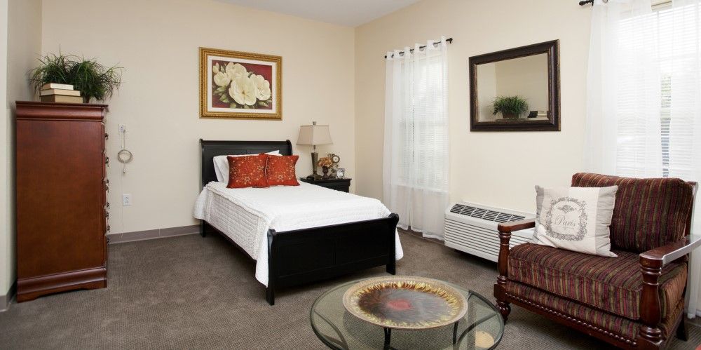A well-decorated bedroom with a single bed, bedside lamp, and framed artwork on the wall.