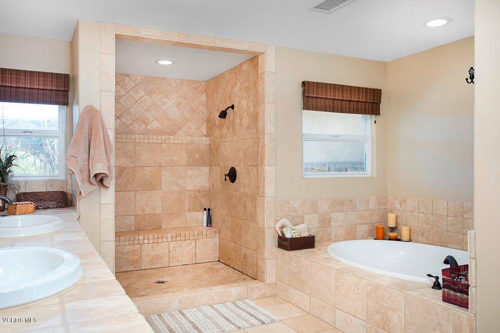 A modern bathroom with tiled shower and bathtub.