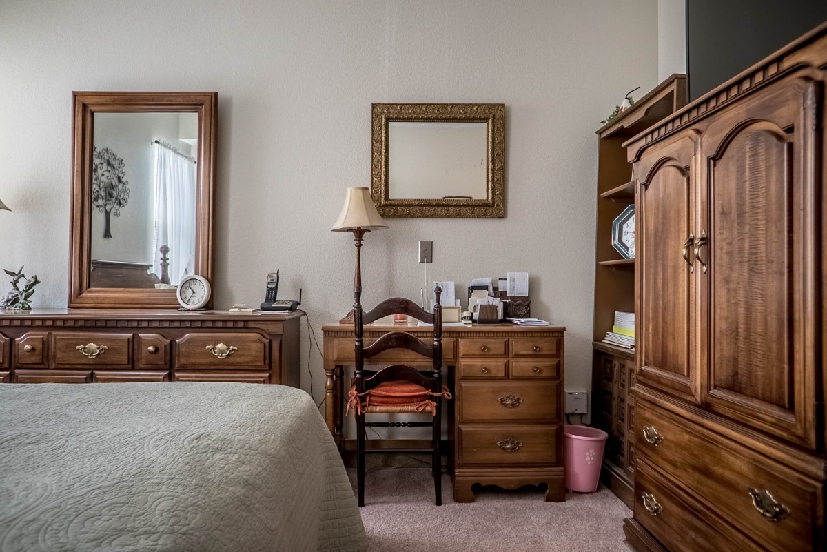 A cozy bedroom with wooden furniture, including a dresser, mirror, and desk.