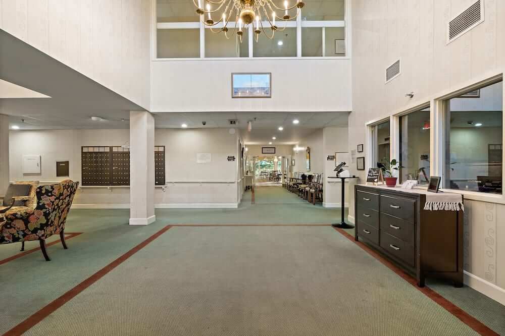 A spacious lobby area with a chandelier, reception desk, and mailboxes.