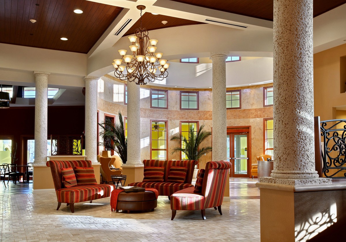 A spacious and elegantly designed lobby featuring a chandelier, comfortable seating, and large windows.