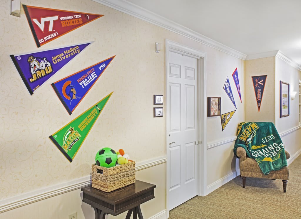 A hallway adorned with colorful college pennants and a basket containing a soccer ball.