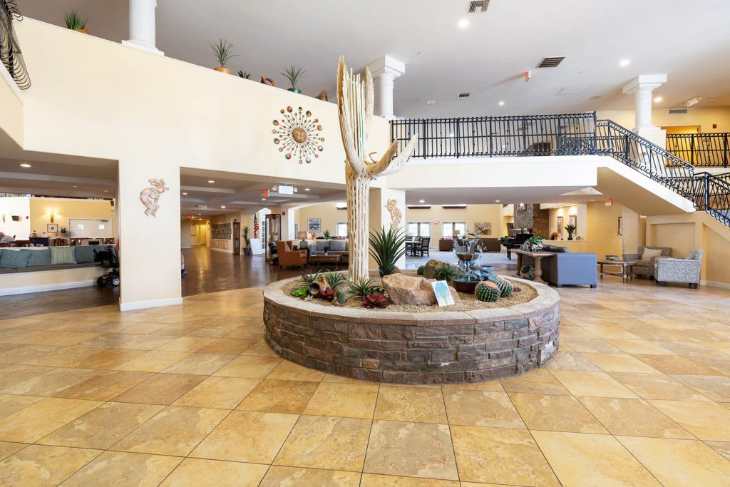 A spacious hotel lobby featuring a large cactus centerpiece surrounded by tiled flooring and modern decor.