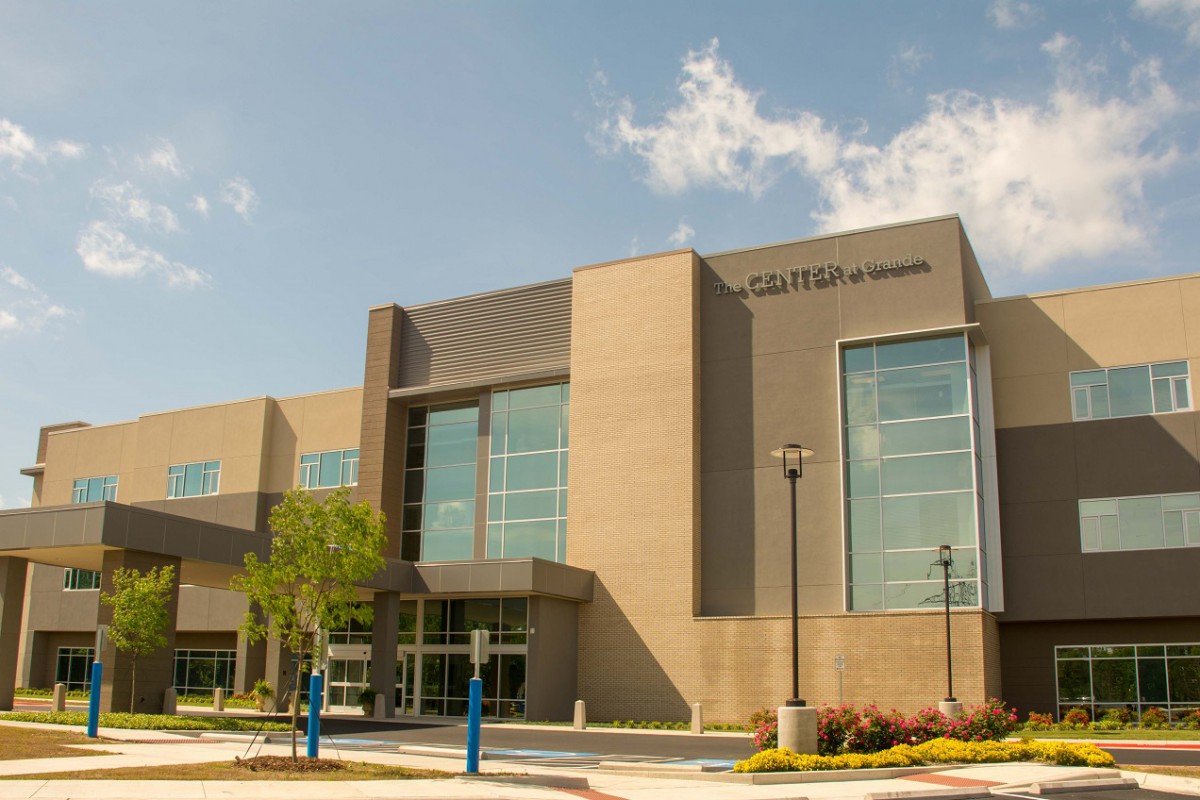 A modern educational building with large windows under a partly cloudy sky.